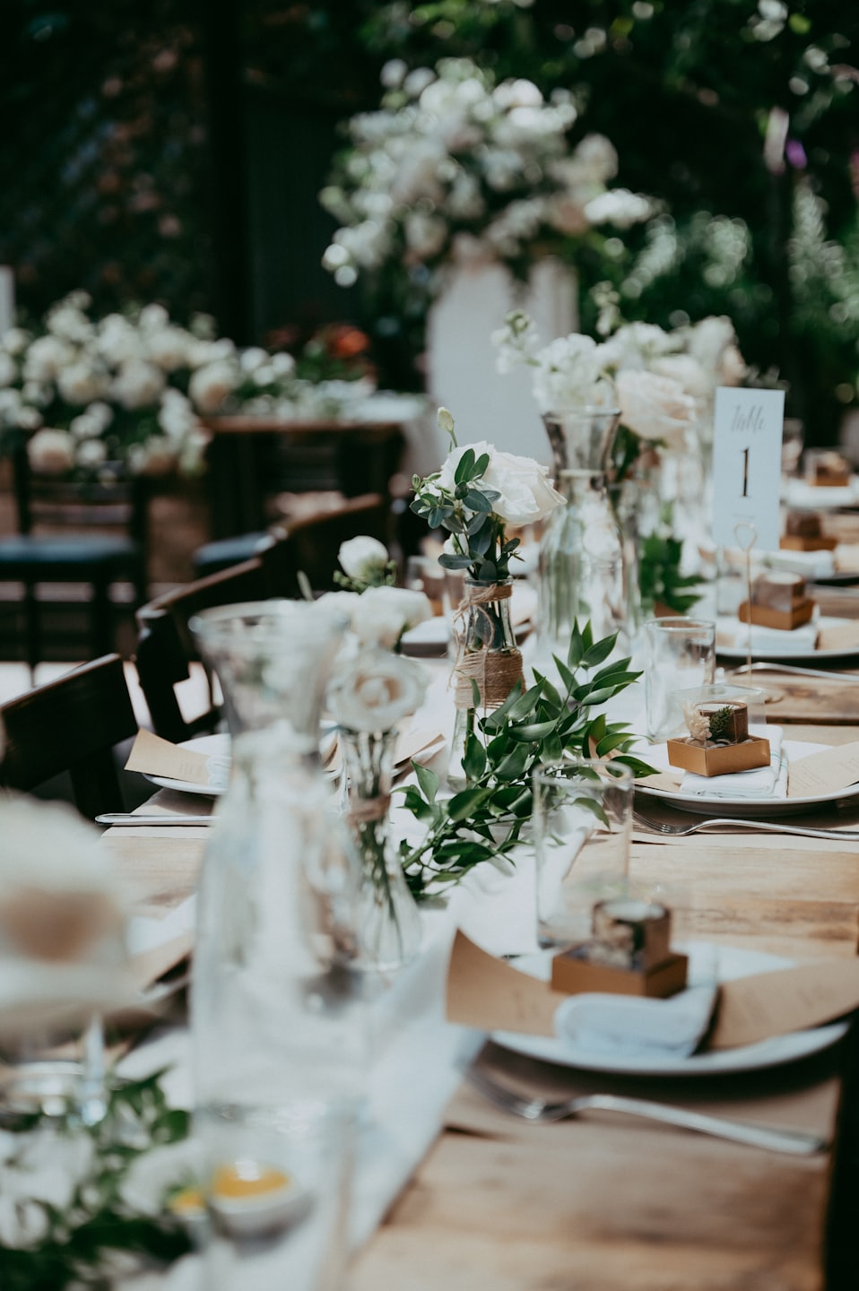 Elegant wooden table set with floral arrangements and place settings.